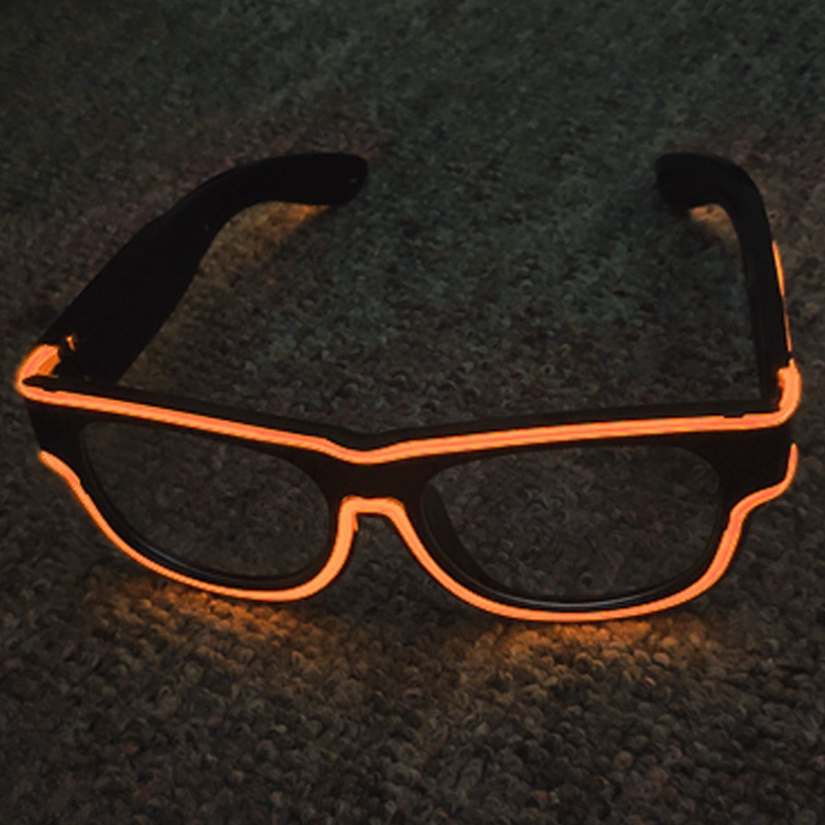 Black sunglasses with orange EL wire frame on a dark textured surface